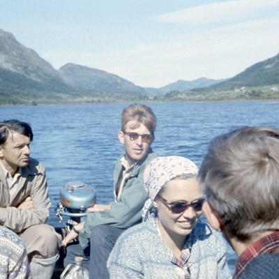 Fem personer sitter i båt på et vann.  